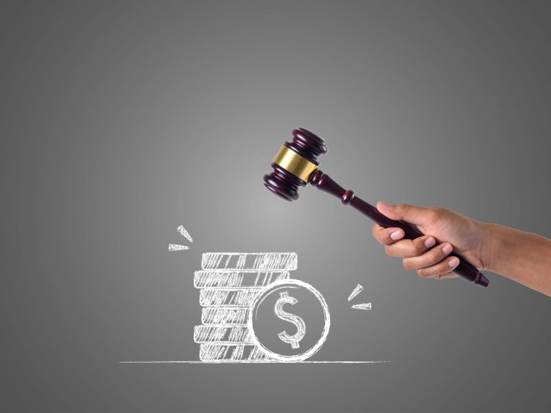The hand that holds the hammer and piles of money written with white chalk, draw concept.