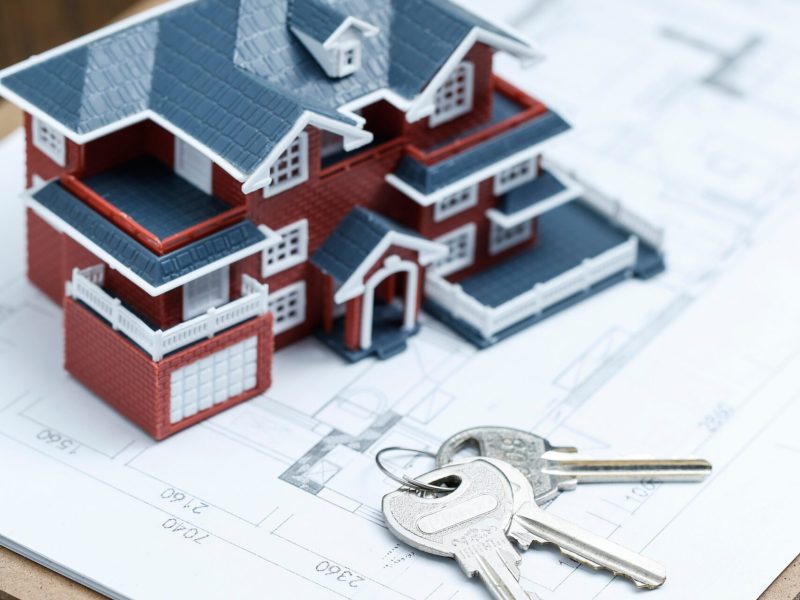 Villa house model, key and drawing on retro desktop (real estate sale concept)